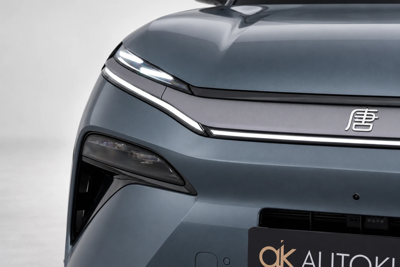 BYD Tang L, zbliżenie na przednią lampę, listwę świetlną i emblemat na masce.