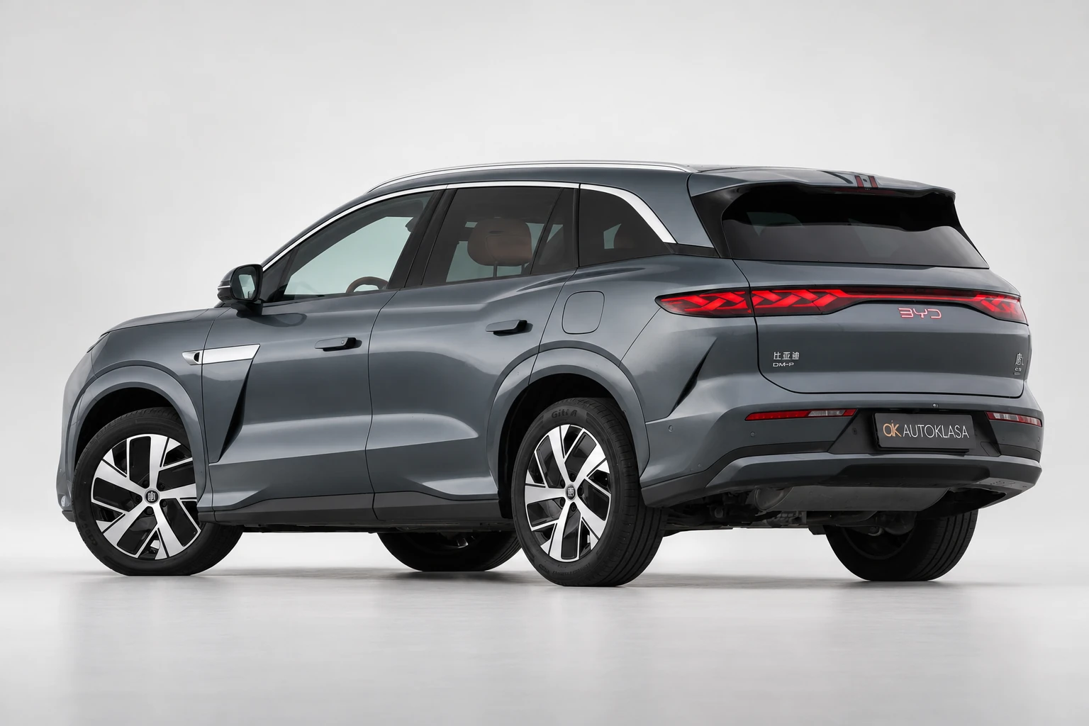 BYD Tang L od tyłu pod kątem, z widocznym bokiem, kołami i czerwoną listwą lamp.