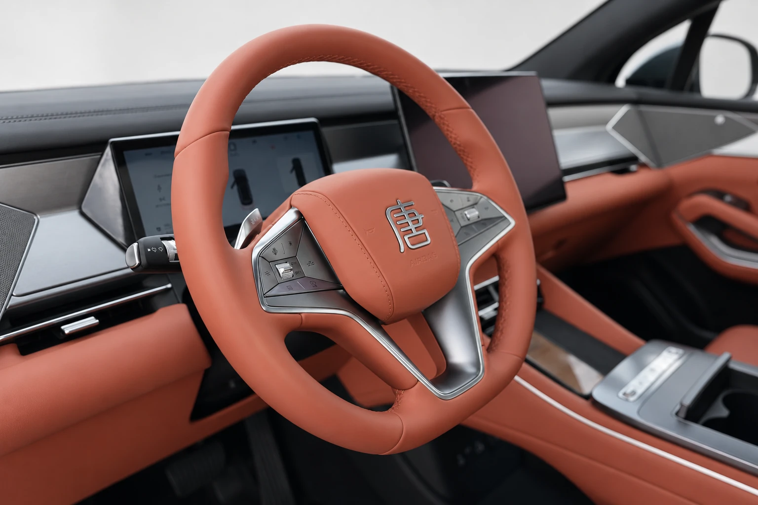 BYD Tang L, miejsce kierowcy z koniakową kierownicą i ciemnym centralnym ekranem.