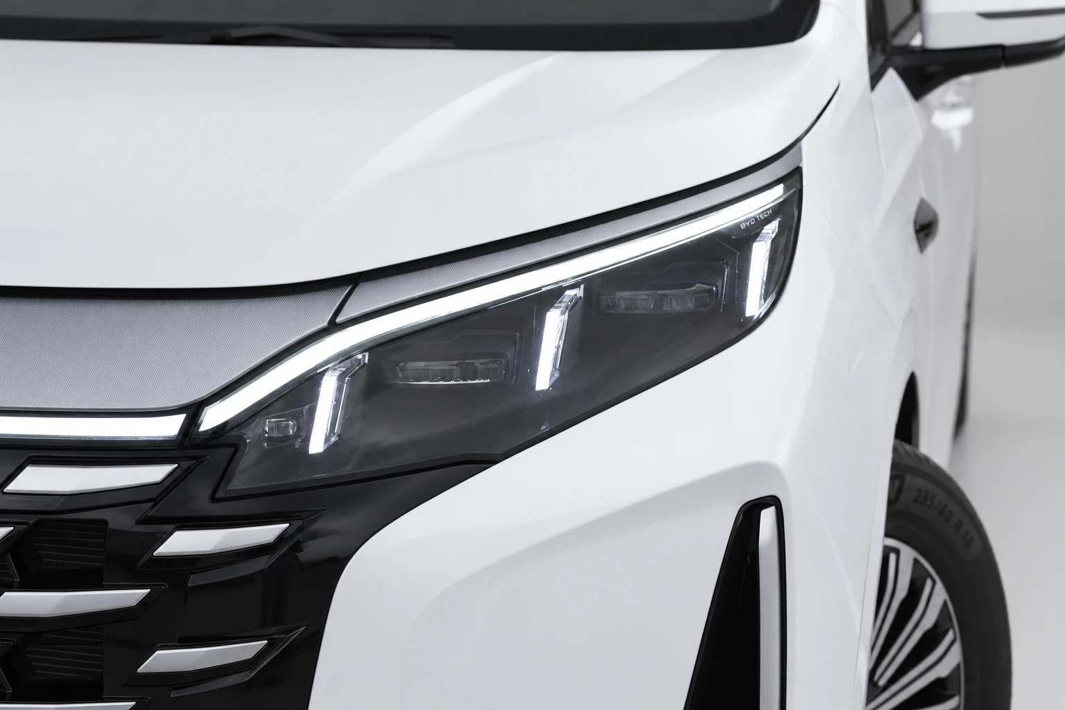BYD Xia, bliższy kadr przedniej lampy ze świetlną listwą i pionowymi elementami wewnątrz klosza.
