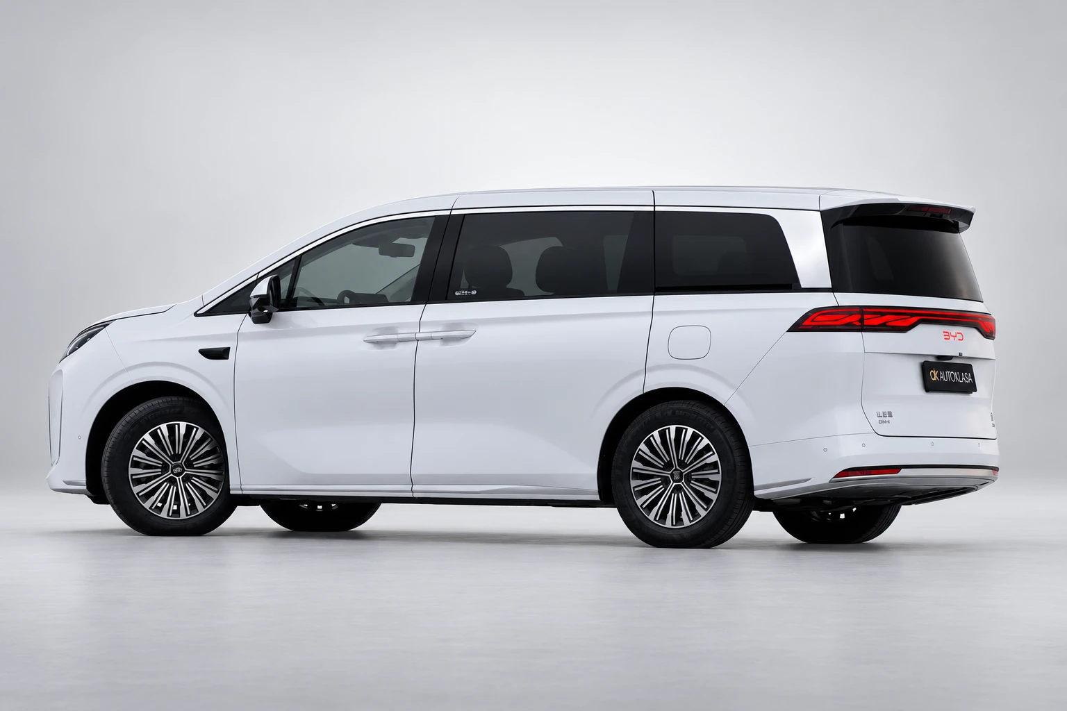 BYD Xia od boku i tyłu, z przesuwanymi drzwiami, bocznymi szybami i zapalonymi lampami.