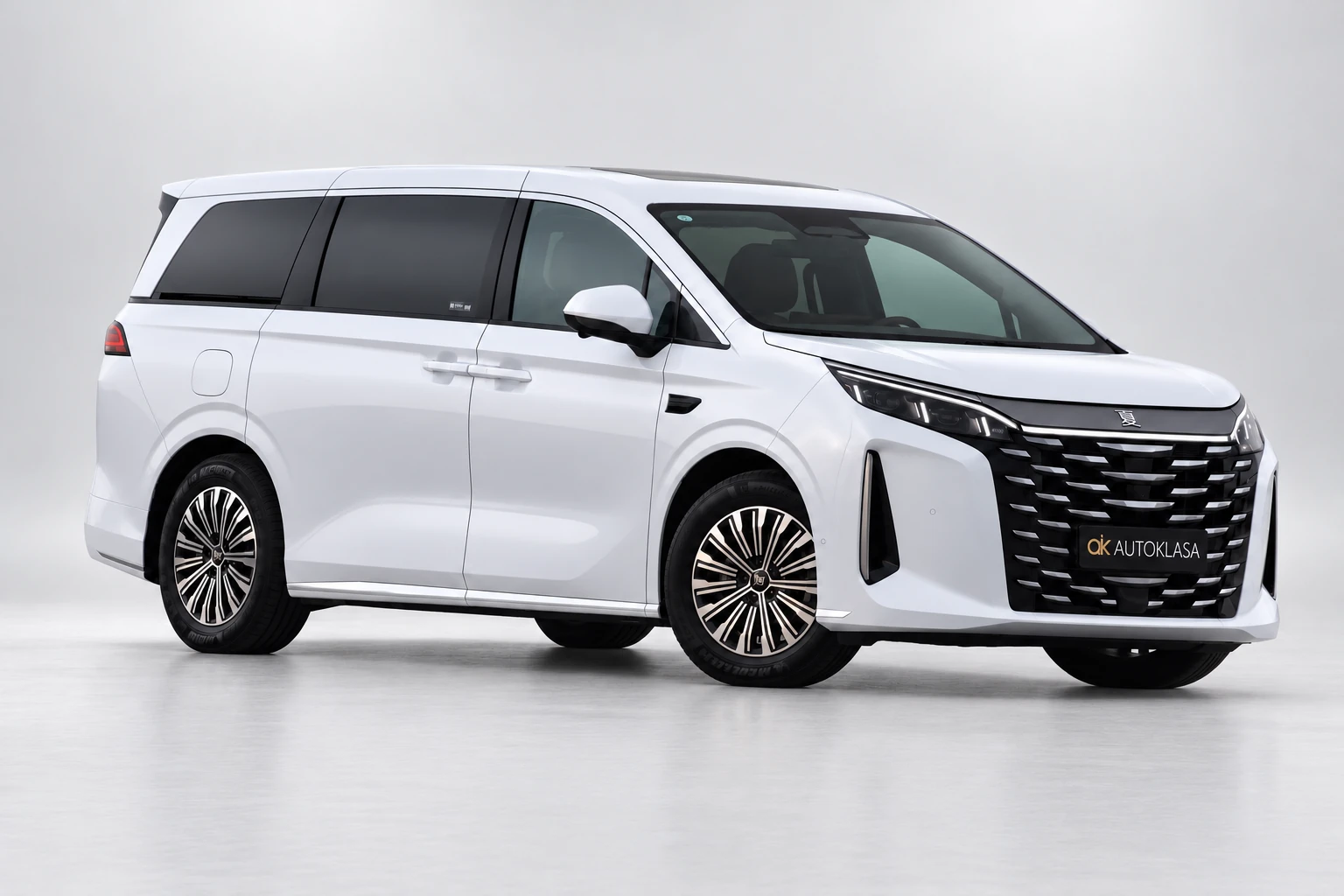 BYD Xia od przodu i boku w bliższym kadrze, z widocznymi drzwiami przesuwnymi i kołami.
