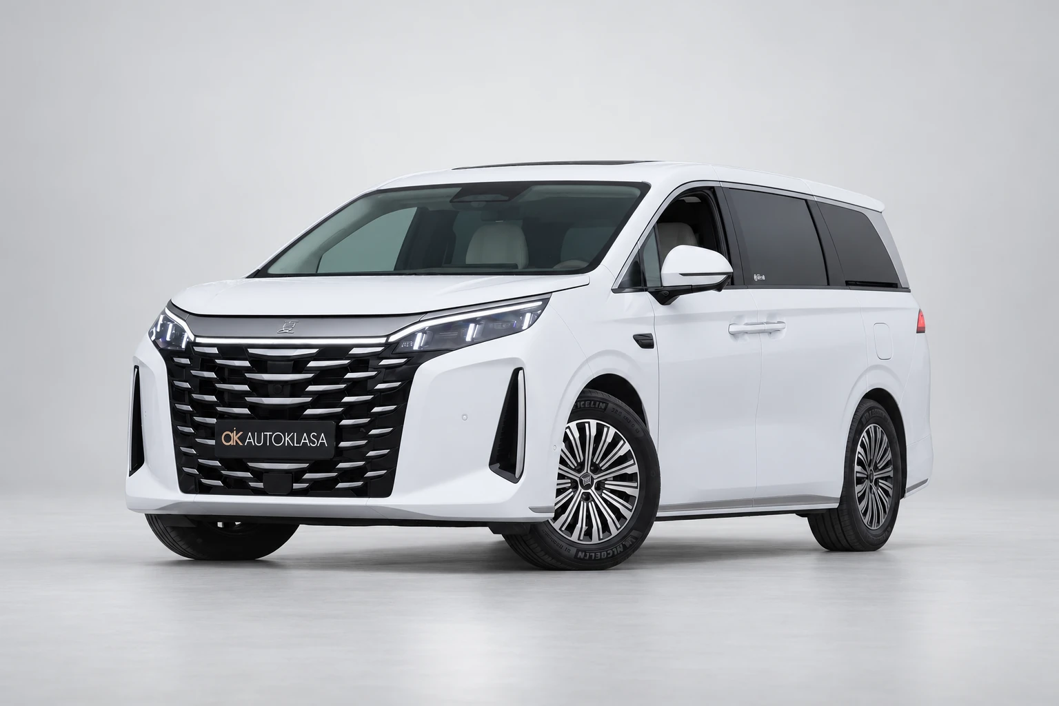 BYD Xia od przodu i drugiego boku w jasnym studiu, z całą białą sylwetką i wieloramiennymi kołami; ujęcie 1.