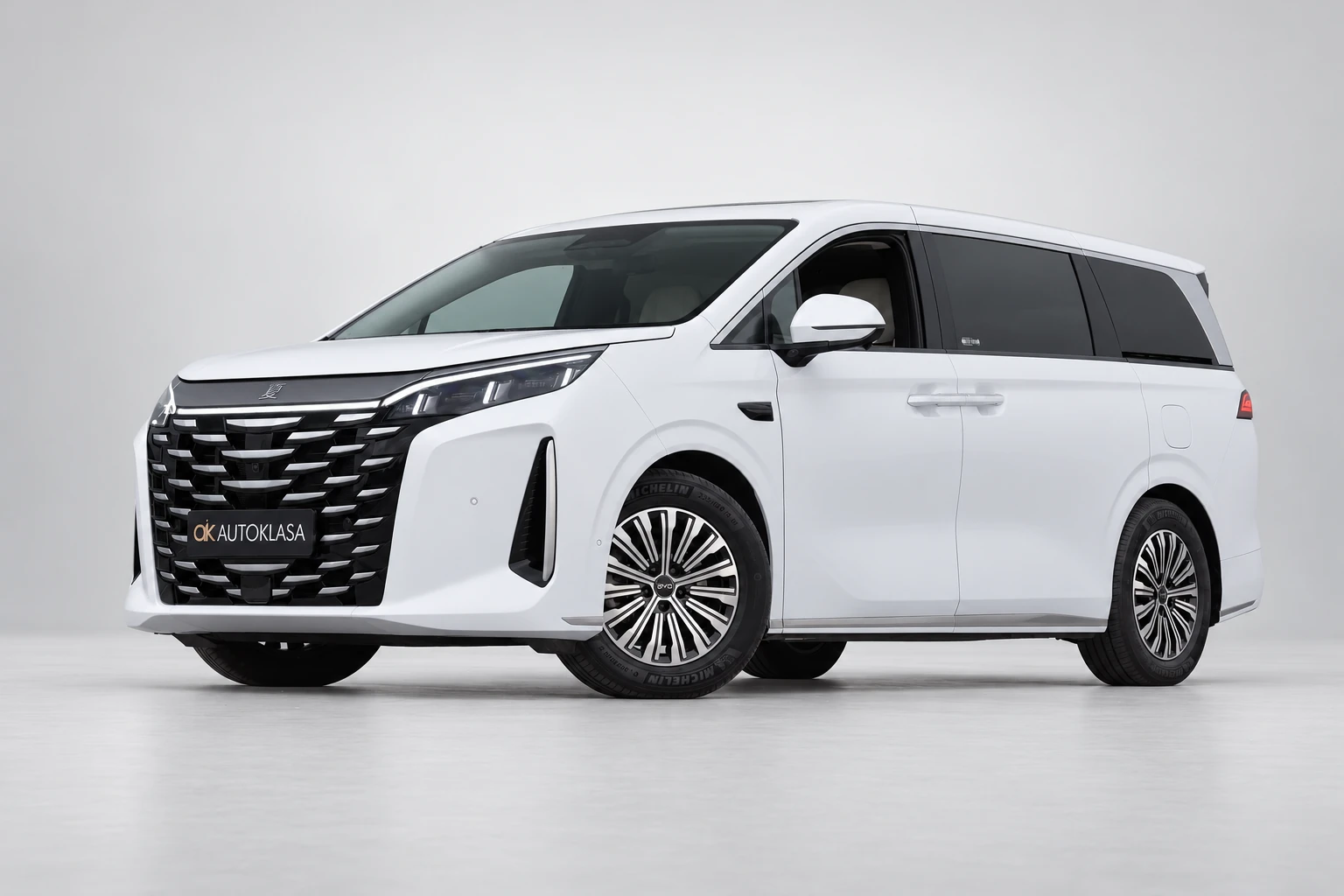 BYD Xia od przodu i drugiego boku w jasnym studiu, z całą białą sylwetką i wieloramiennymi kołami; ujęcie 4.