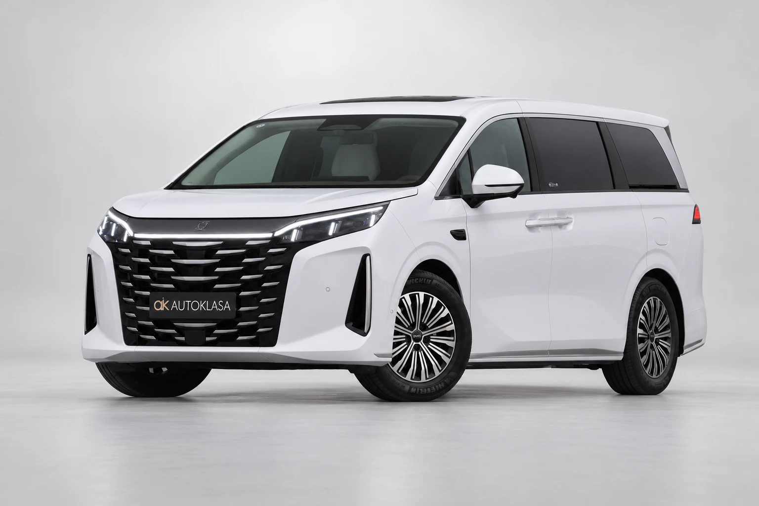 BYD Xia od przodu i drugiego boku w jasnym studiu, z całą białą sylwetką i wieloramiennymi kołami; ujęcie 8.