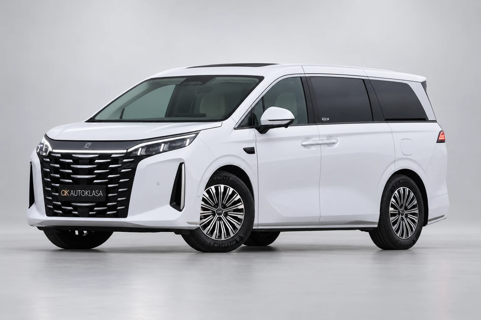 BYD Xia od przodu i drugiego boku w jasnym studiu, z całą białą sylwetką i wieloramiennymi kołami; ujęcie 11.