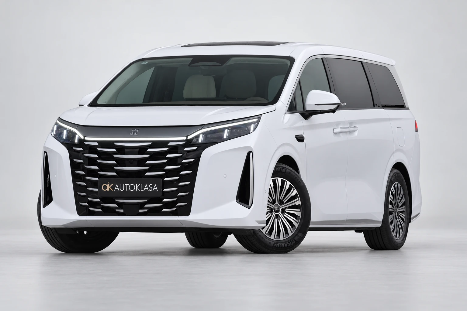 BYD Xia od przodu i drugiego boku w jasnym studiu, z całą białą sylwetką i wieloramiennymi kołami; ujęcie 13.