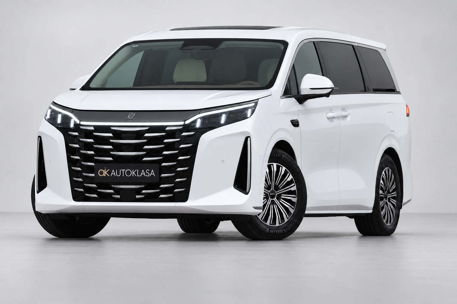 BYD Xia od przodu i drugiego boku w jasnym studiu, z całą białą sylwetką i wieloramiennymi kołami; ujęcie 14.