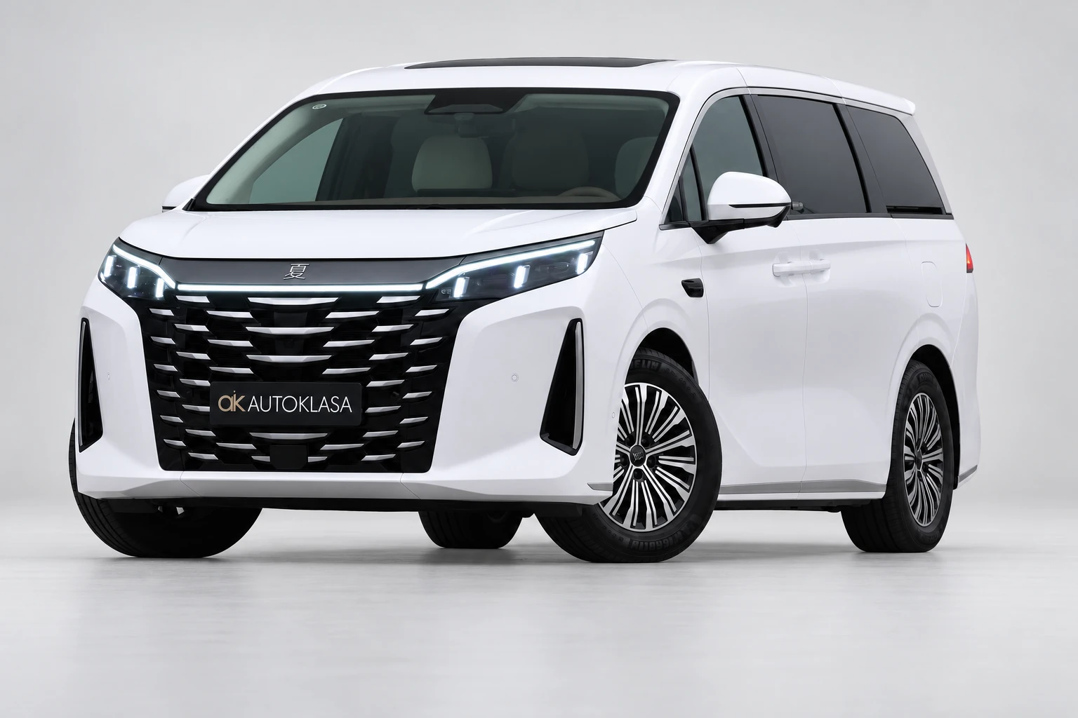 BYD Xia od przodu i drugiego boku w jasnym studiu, z całą białą sylwetką i wieloramiennymi kołami; ujęcie 15.