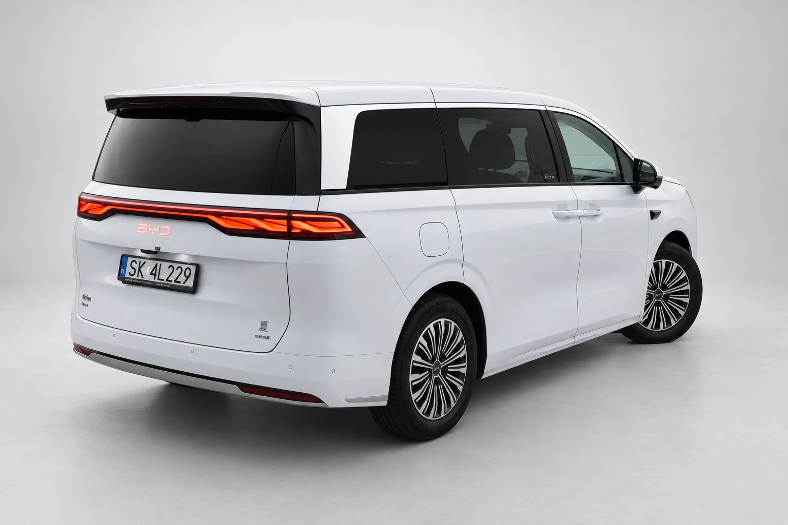 BYD Xia od tyłu i drugiego boku, z czerwoną listwą lamp, ciemnymi szybami i białym nadwoziem; ujęcie 1.