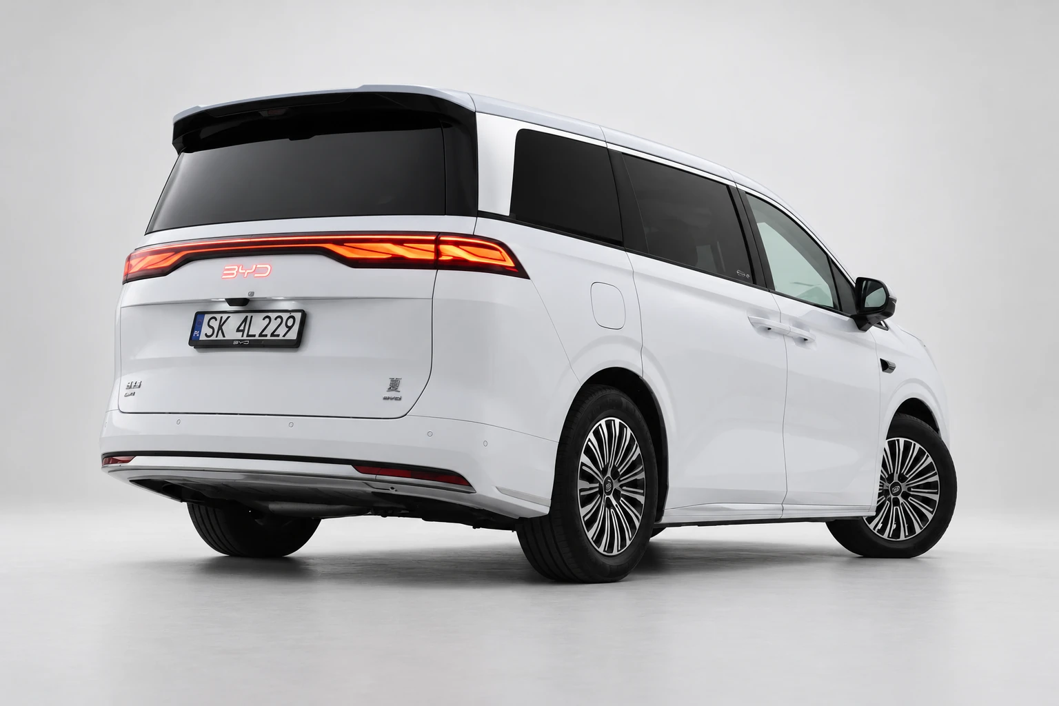 BYD Xia od tyłu i drugiego boku, z czerwoną listwą lamp, ciemnymi szybami i białym nadwoziem; ujęcie 3.