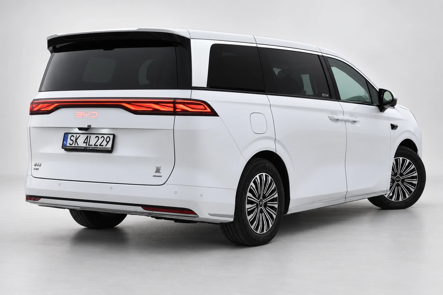 BYD Xia od tyłu i drugiego boku, z czerwoną listwą lamp, ciemnymi szybami i białym nadwoziem; ujęcie 4.
