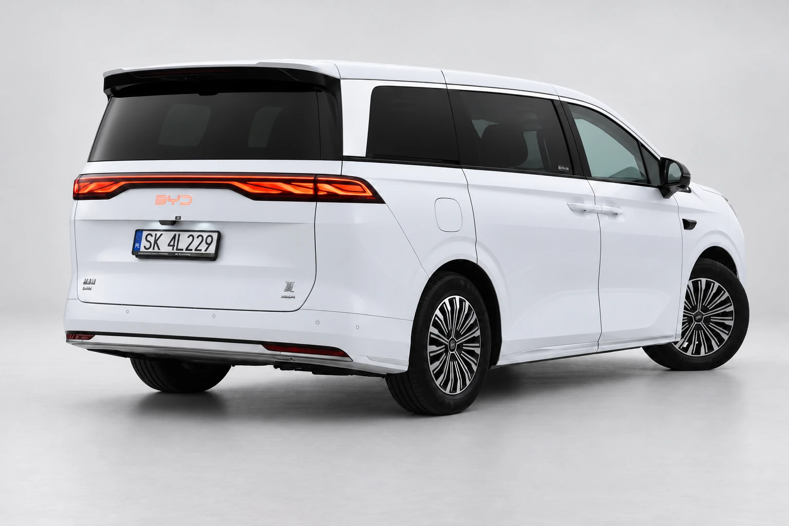 BYD Xia od tyłu i drugiego boku, z czerwoną listwą lamp, ciemnymi szybami i białym nadwoziem; ujęcie 5.