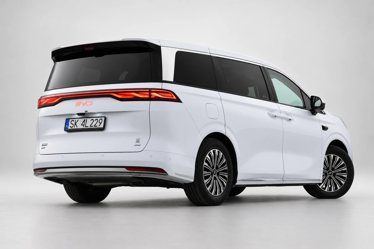 BYD Xia od tyłu i drugiego boku, z czerwoną listwą lamp, ciemnymi szybami i białym nadwoziem; ujęcie 7.