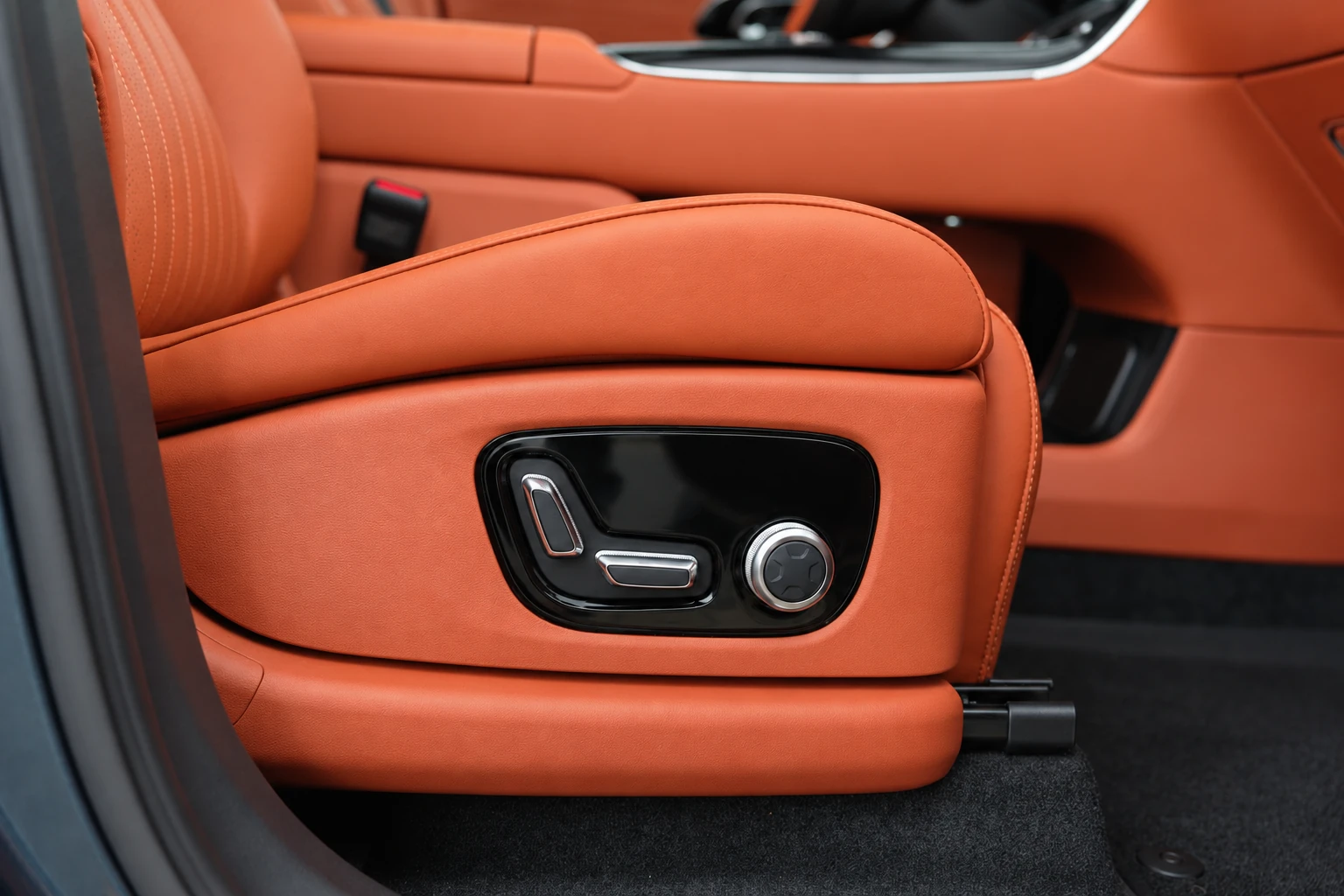 Panel drugiego fotela Geely Galaxy M9 z pokrętłem, srebrnymi przełącznikami i podłokietnikiem.