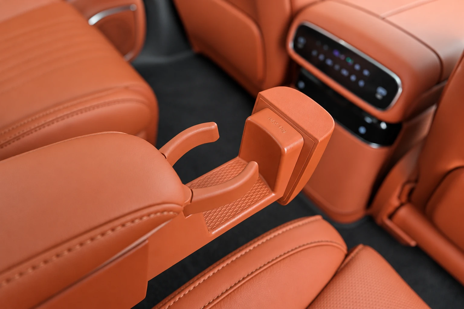 Rozłożony uchwyt na kubek obok fotela Geely Galaxy M9, z panelem nawiewów w tle.
