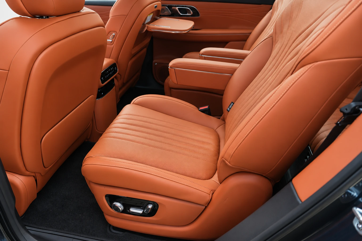 Fotele drugiego rzędu Geely Galaxy M9 z pomarańczową tapicerką i podłokietnikami.