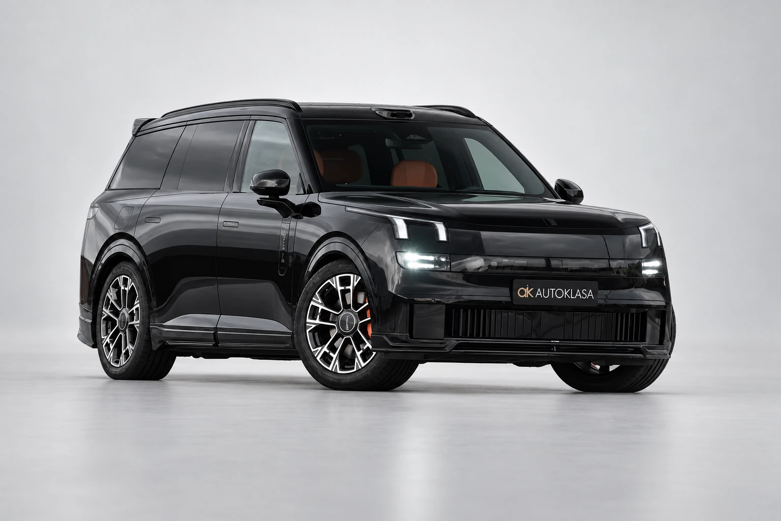 Lynk & Co 900 z przodu pod kątem z włączonymi światłami.